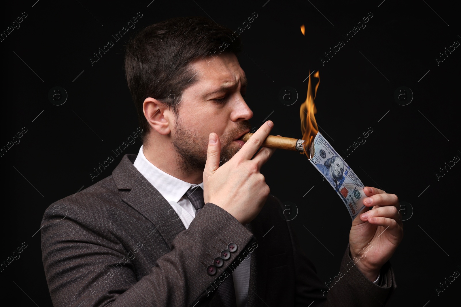 Greedy businessman lighting cigar with dollar banknote on black background Image of Greedy businessman lighting cigar with dollar banknote on black background