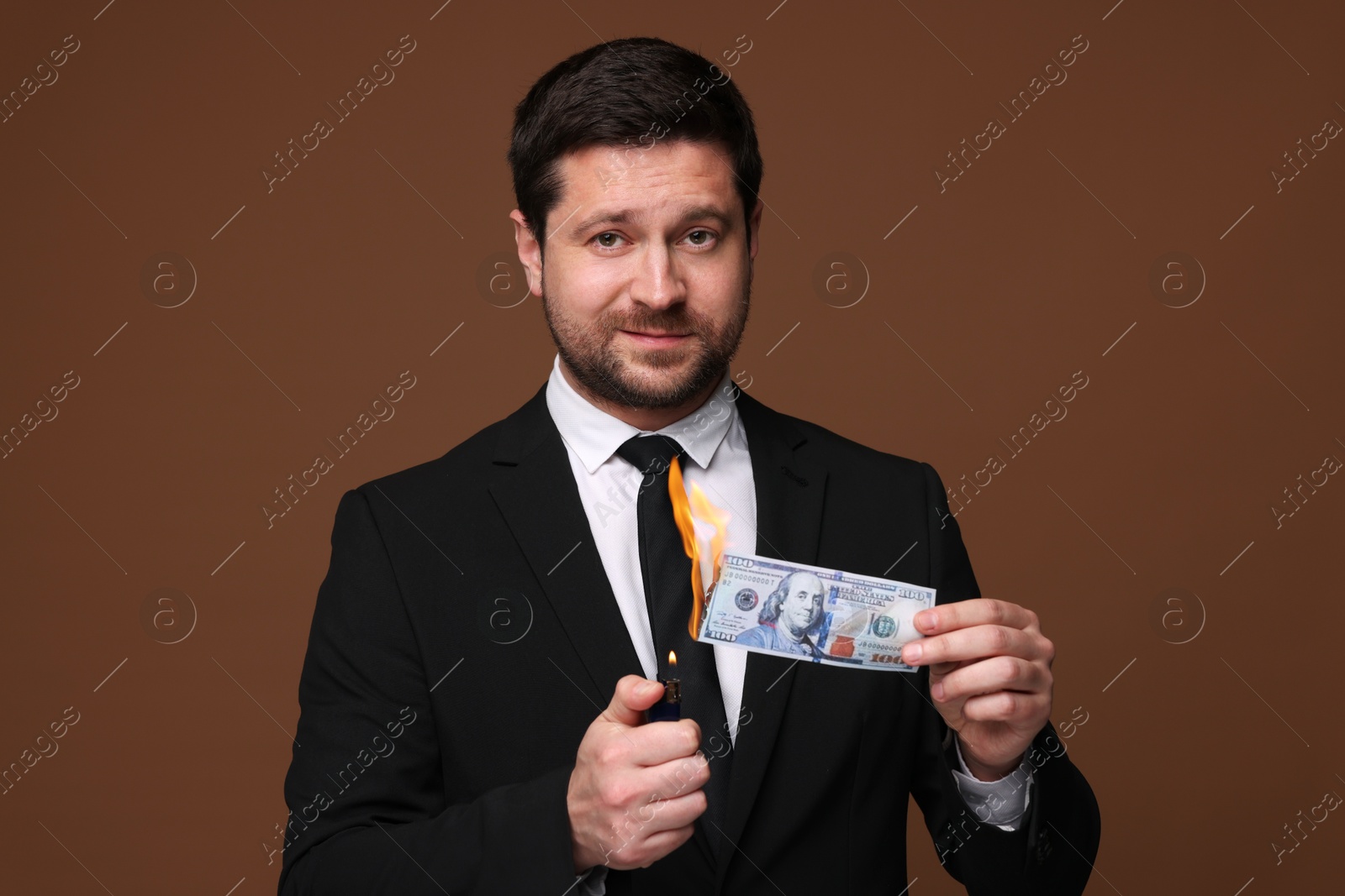 Greedy businessman burning dollar banknote with lighter on brown background Image of Greedy businessman burning dollar banknote with lighter on brown background