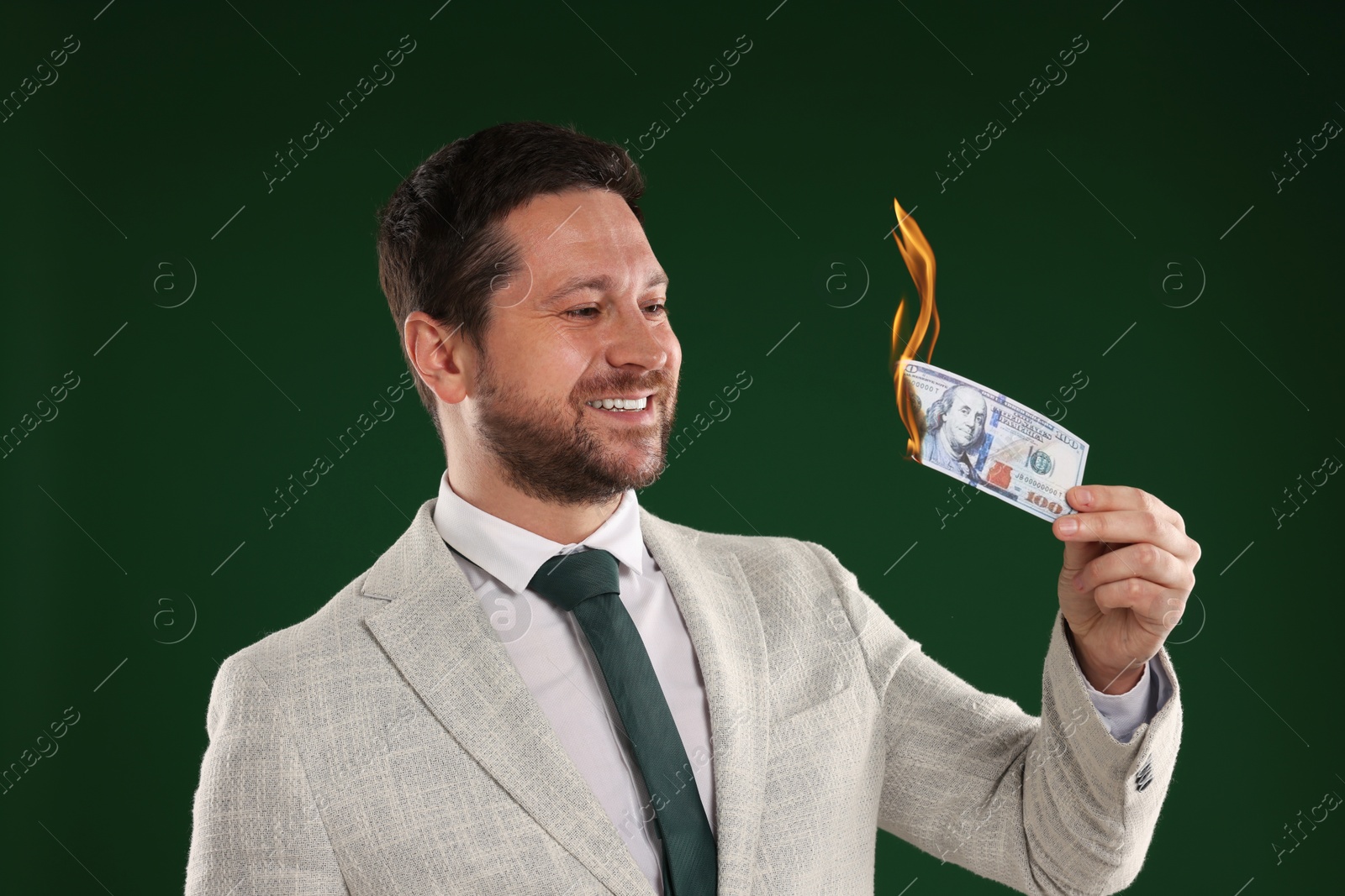 Greedy businessman with burning dollar banknote on dark green background Image of Greedy businessman with burning dollar banknote on dark green background