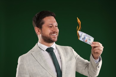 Image of Greedy businessman with burning dollar banknote on dark green background