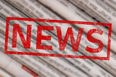 Image of Red News stamp and newspapers as background, closeup