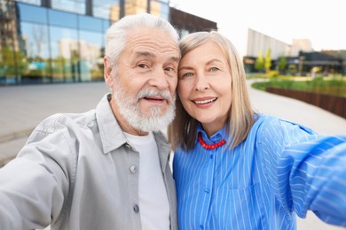 Photo of Lovely senior couple taking selfie on city street