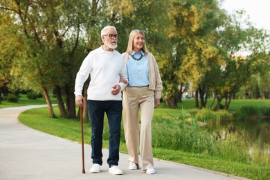 Photo of Lovely senior couple walking together near lake in park