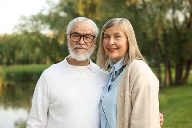Photo of Lovely senior couple walking together near lake in park