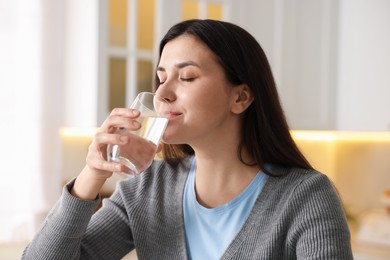 Photo of Woman drinking water from glass in kitchen