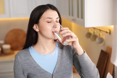 Photo of Woman drinking water from glass in kitchen