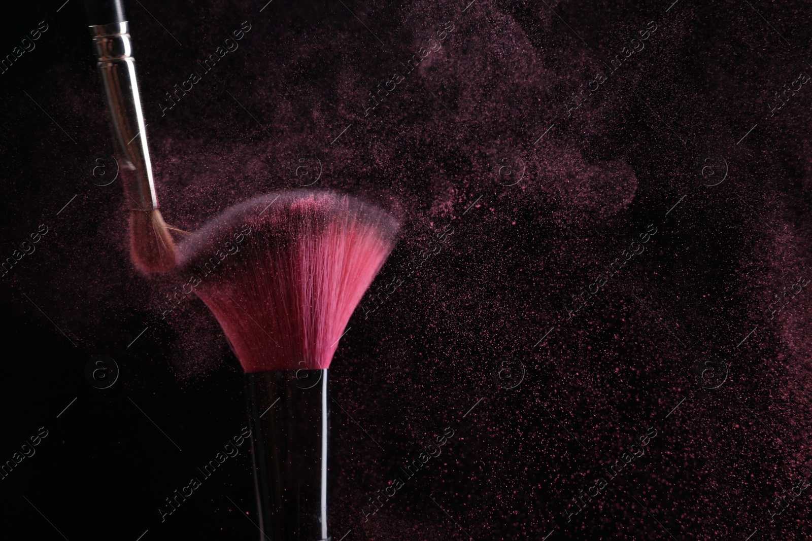 Makeup brushes with pink eye shadow on black background, closeup Photo of Makeup brushes with pink eye shadow on black background, closeup