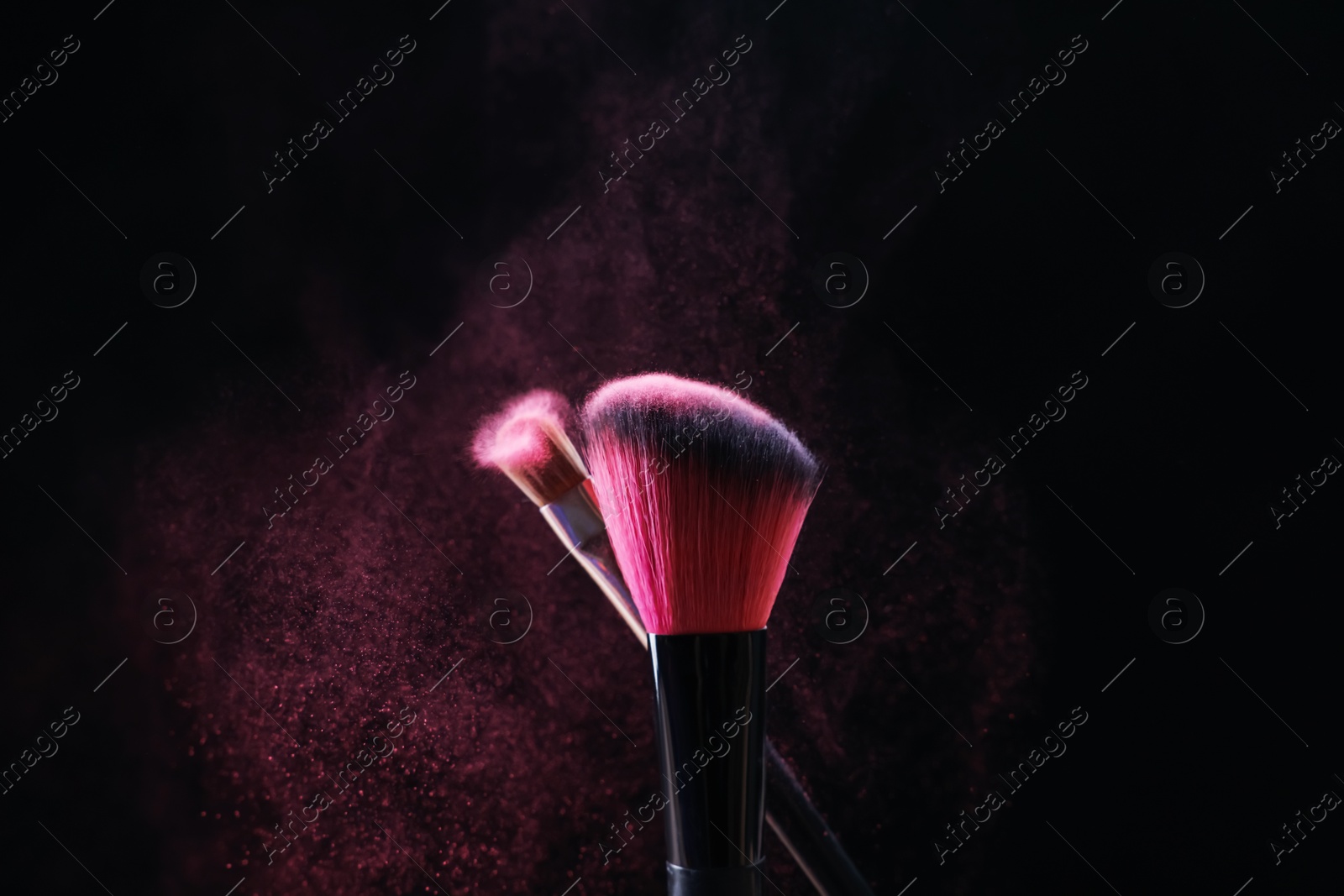 Makeup brushes with pink eye shadow on black background, closeup Photo of Makeup brushes with pink eye shadow on black background, closeup
