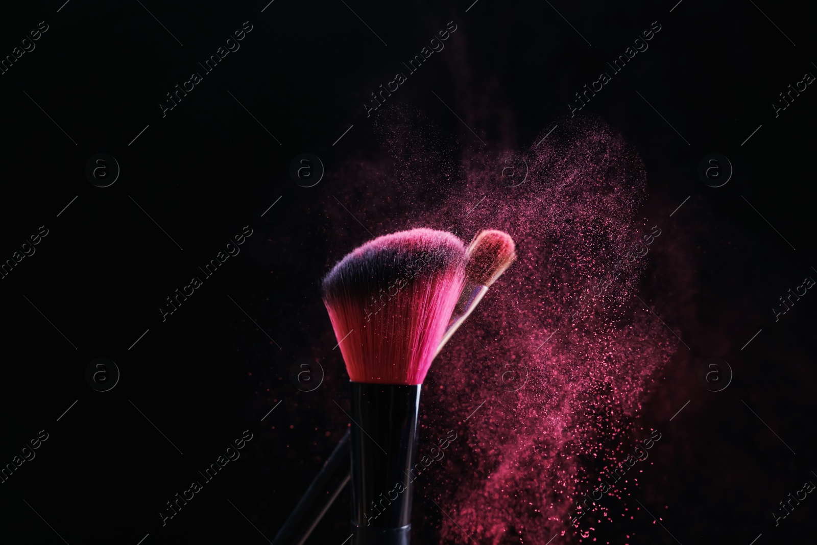 Makeup brushes with pink eye shadow on black background, closeup Photo of Makeup brushes with pink eye shadow on black background, closeup