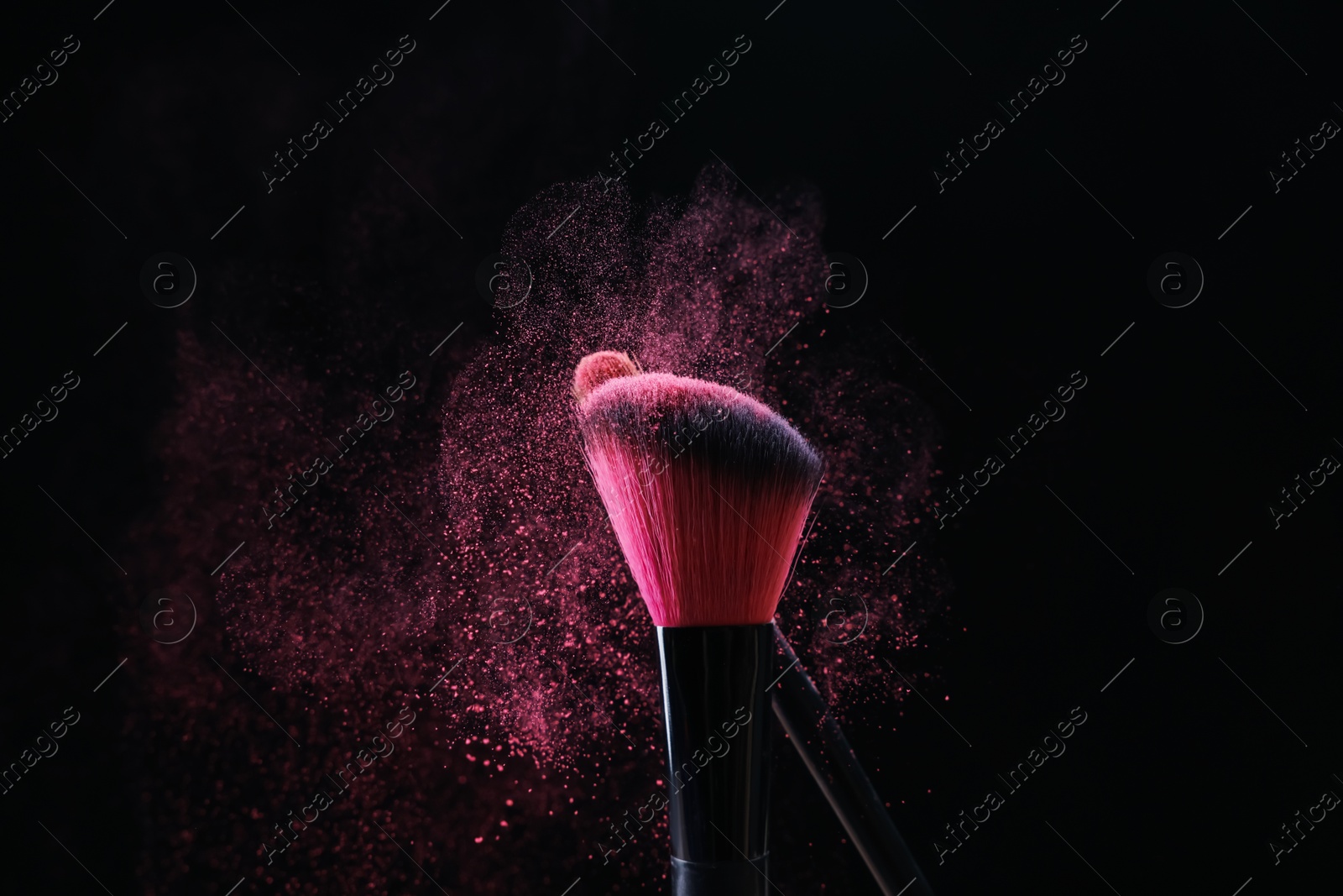 Makeup brushes with pink eye shadow on black background, closeup Photo of Makeup brushes with pink eye shadow on black background, closeup