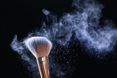 Photo of Makeup brush with cosmetic product on black background, closeup