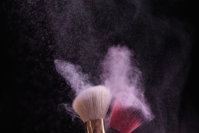 Photo of Makeup brushes with colorful eye shadows on black background, closeup