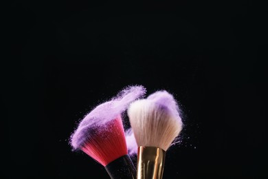 Photo of Makeup brushes with colorful eye shadows on black background, closeup. Space for text