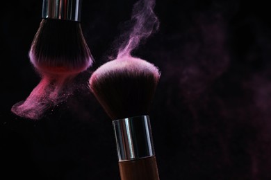 Photo of Makeup brushes with color eye shadow on black background, closeup