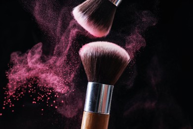 Photo of Makeup brushes with color eye shadow on black background, closeup