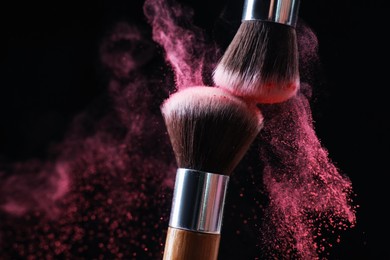 Photo of Makeup brushes with color eye shadow on black background, closeup