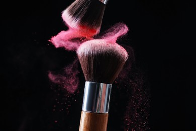 Photo of Makeup brushes with color eye shadow on black background, closeup