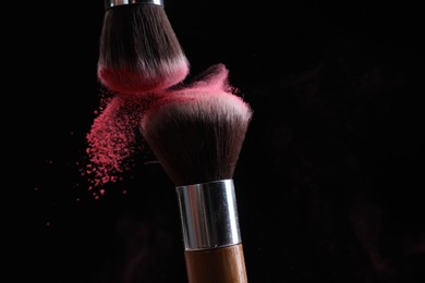 Photo of Makeup brushes with color eye shadow on black background, closeup