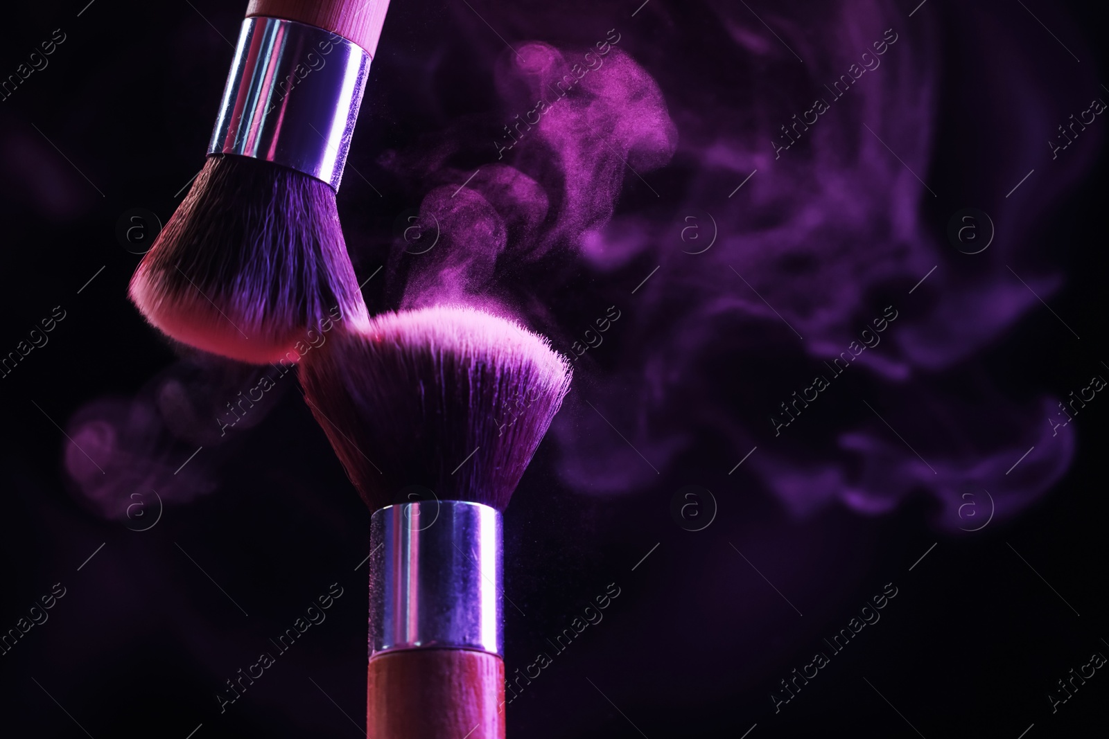 Makeup brushes with purple eye shadow in neon lights on black background, closeup. Space for text Photo of Makeup brushes with purple eye shadow in neon lights on black background, closeup. Space for text