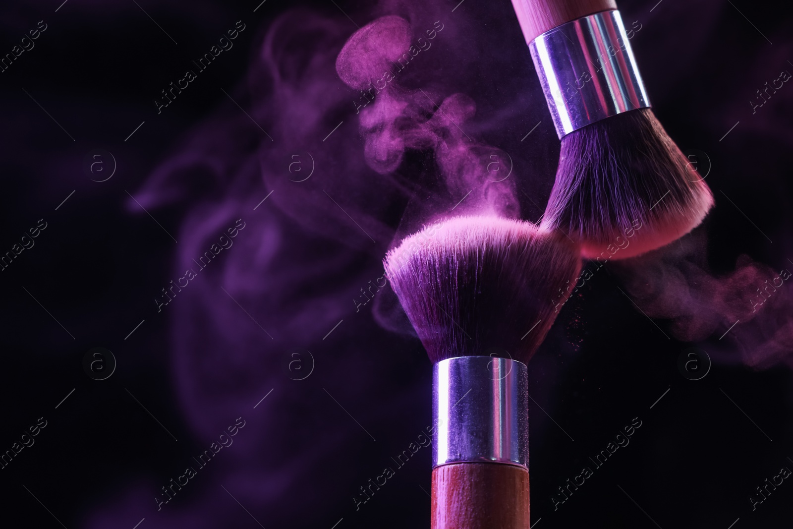Makeup brushes with purple eye shadow in neon lights on black background, closeup. Space for text Photo of Makeup brushes with purple eye shadow in neon lights on black background, closeup. Space for text