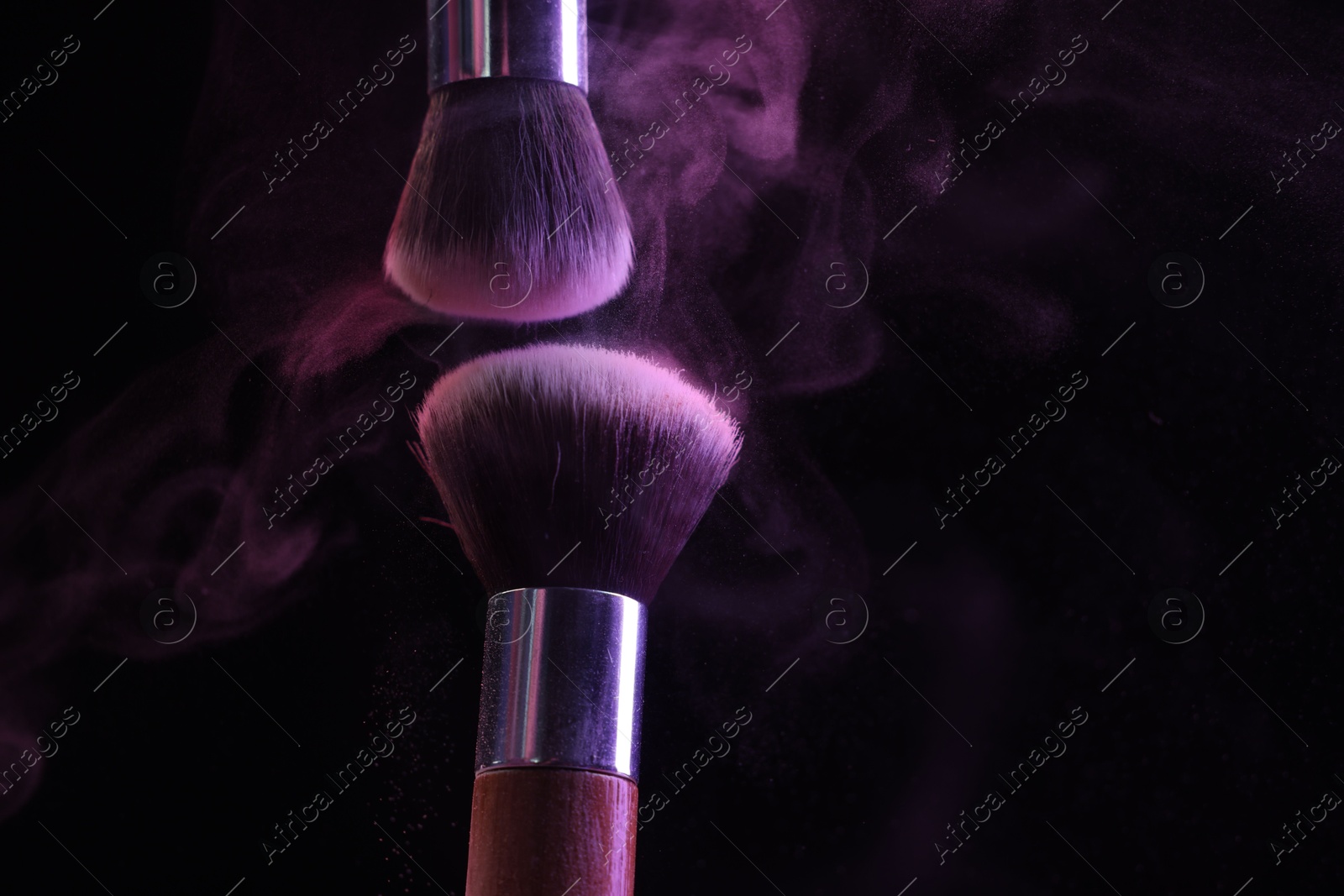 Makeup brushes with purple eye shadow in neon lights on black background, closeup. Space for text Photo of Makeup brushes with purple eye shadow in neon lights on black background, closeup. Space for text