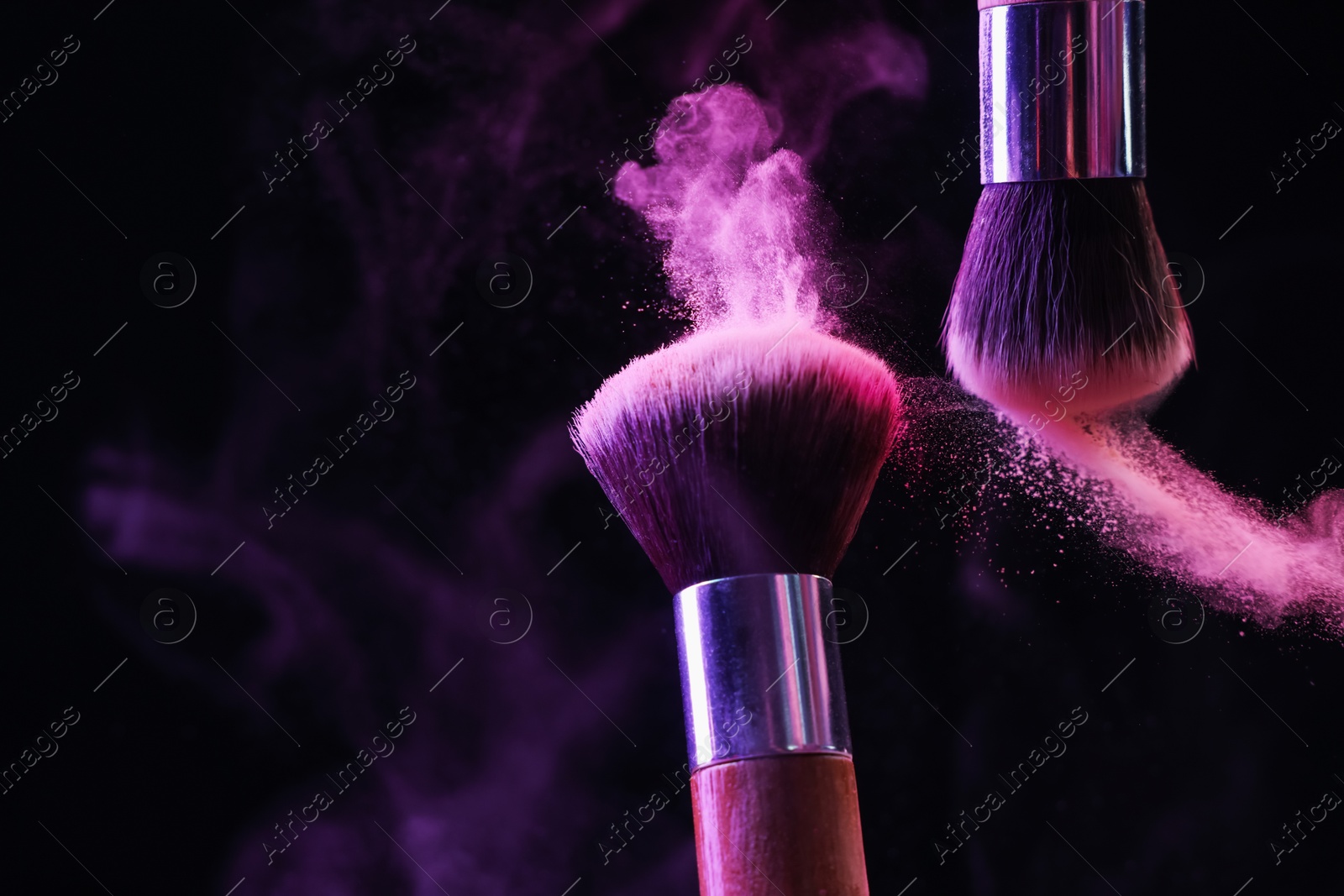 Makeup brushes with colorful eye shadows in neon lights on black background, closeup. Space for text Photo of Makeup brushes with colorful eye shadows in neon lights on black background, closeup. Space for text