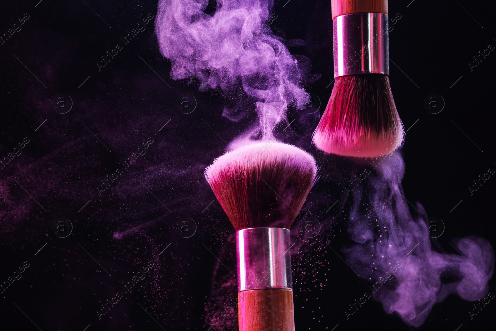 Makeup brushes with colorful eye shadows in neon lights on black background, closeup Photo of Makeup brushes with colorful eye shadows in neon lights on black background, closeup