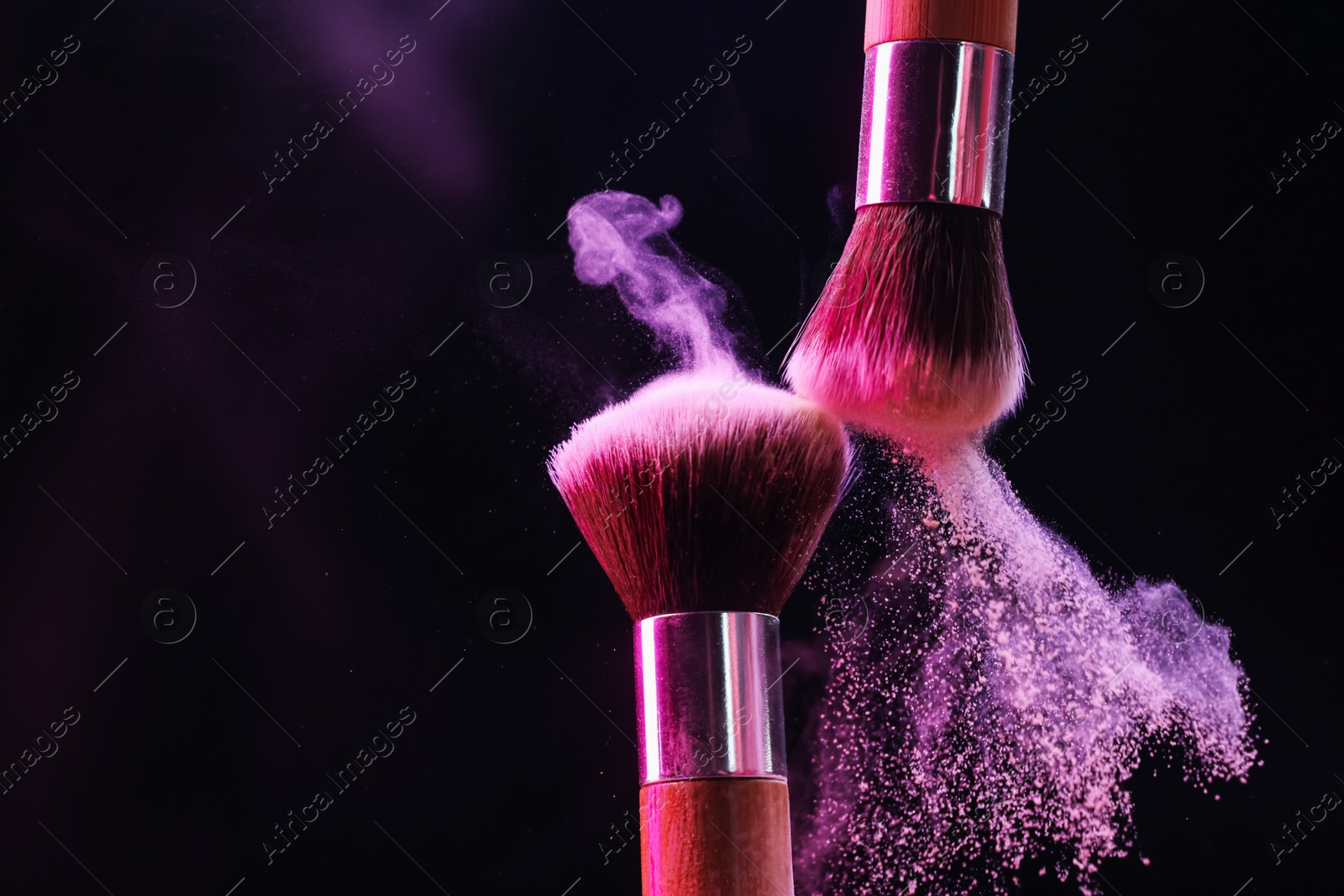Makeup brushes with colorful eye shadows in neon lights on black background, closeup Photo of Makeup brushes with colorful eye shadows in neon lights on black background, closeup