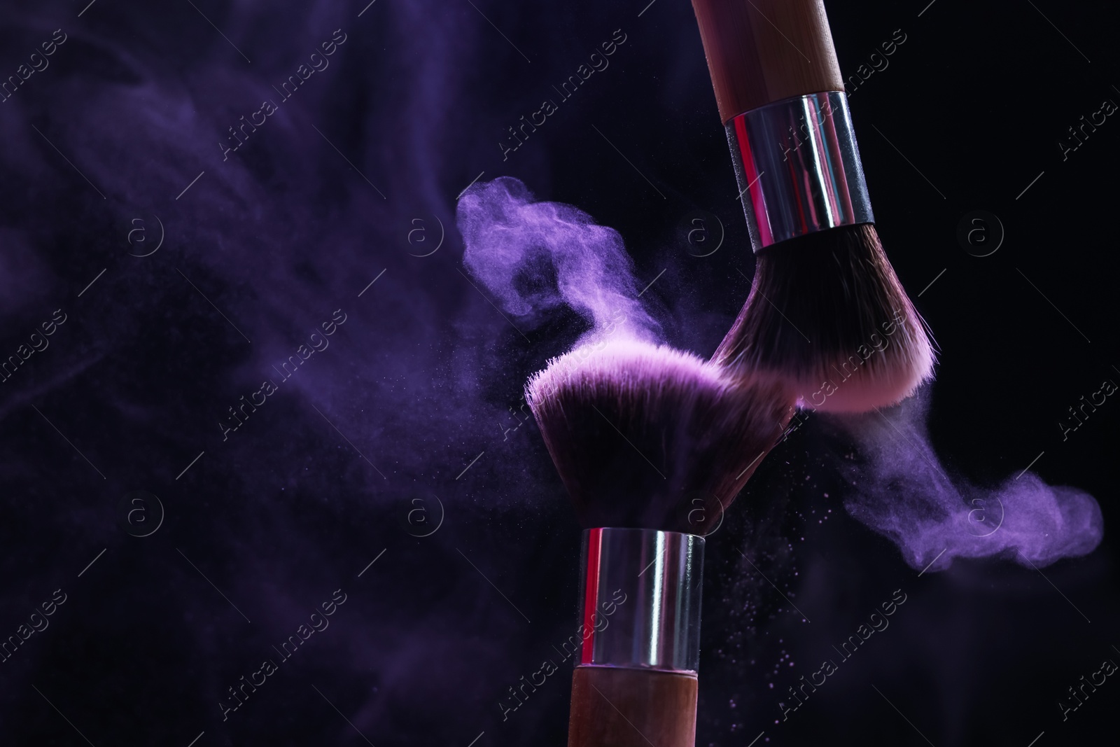 Makeup brushes with purple eye shadow in neon lights on black background, closeup. Space for text Photo of Makeup brushes with purple eye shadow in neon lights on black background, closeup. Space for text