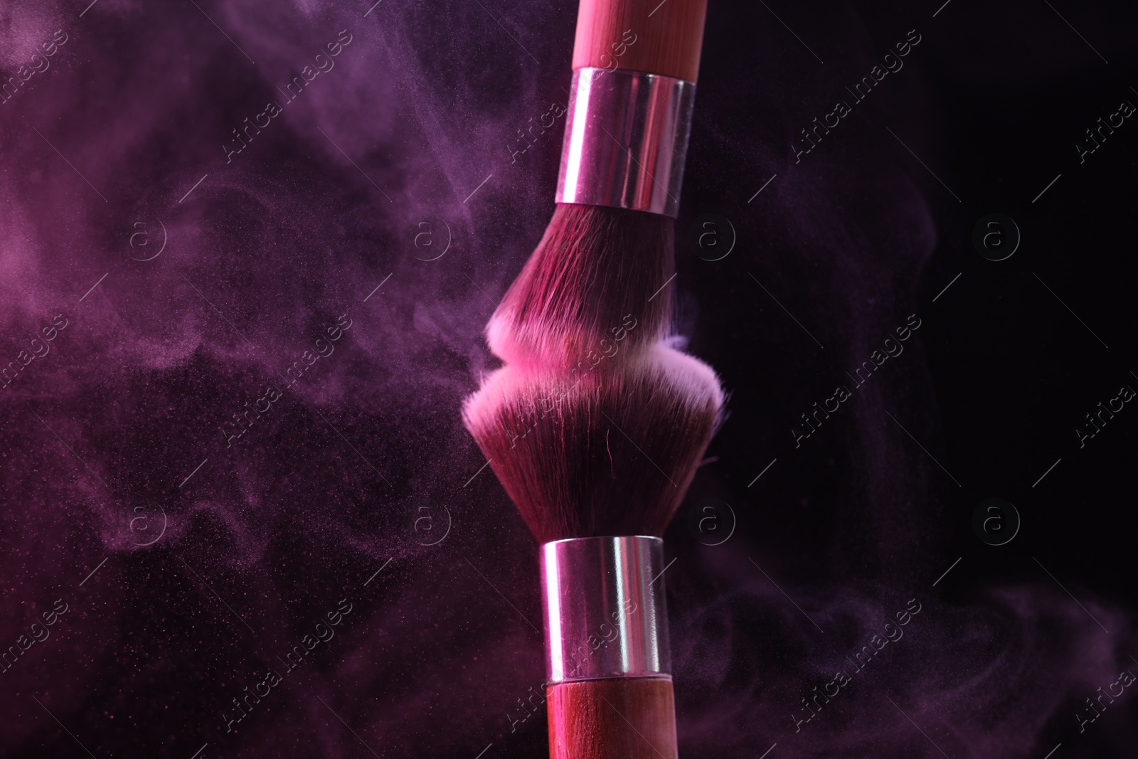Makeup brushes with pink eye shadow on black background, closeup Photo of Makeup brushes with pink eye shadow on black background, closeup