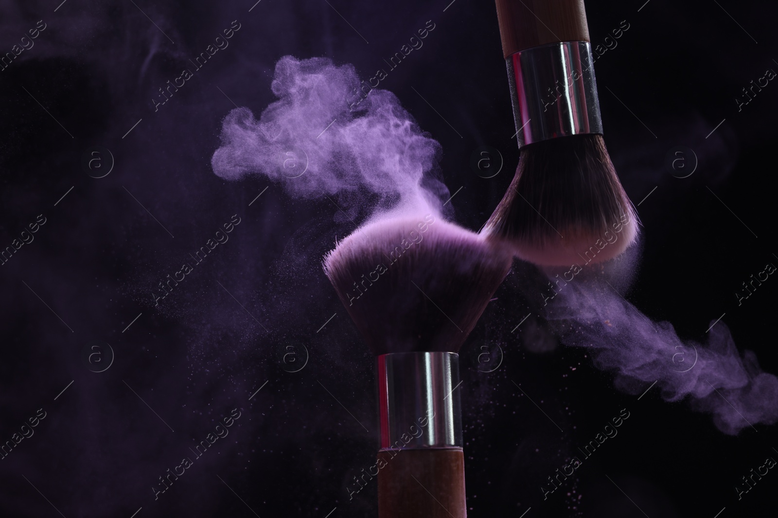 Makeup brushes with purple eye shadow on black background, closeup Photo of Makeup brushes with purple eye shadow on black background, closeup