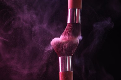Photo of Makeup brushes with colorful eye shadows on black background, closeup