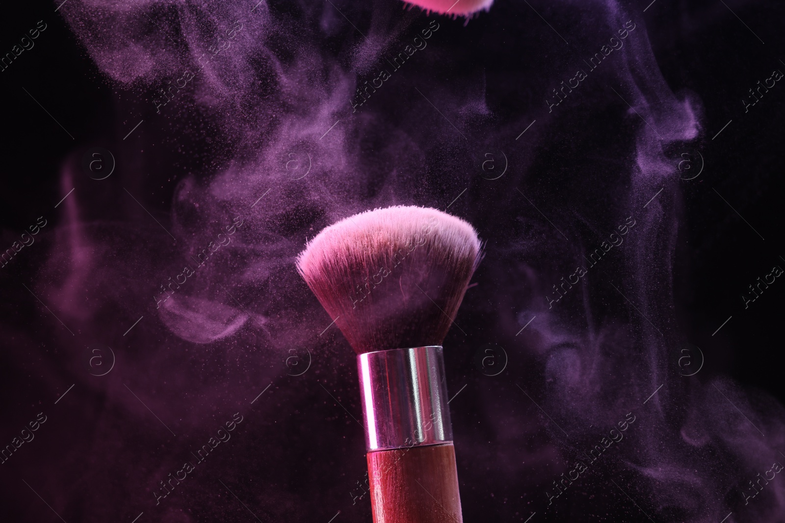 Makeup brush with color eye shadow in neon lights on black background, closeup Photo of Makeup brush with color eye shadow in neon lights on black background, closeup