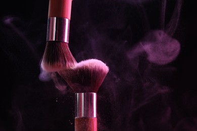 Photo of Makeup brushes with colorful eye shadows on black background, closeup
