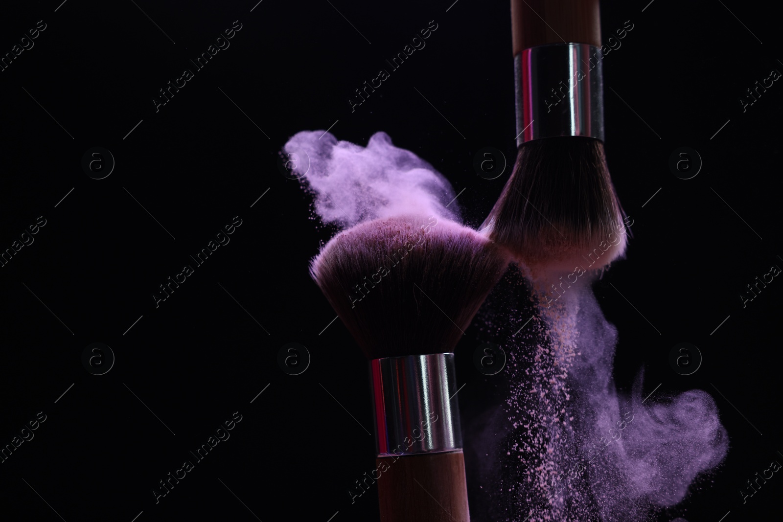 Makeup brushes with purple eye shadow on black background, closeup Photo of Makeup brushes with purple eye shadow on black background, closeup