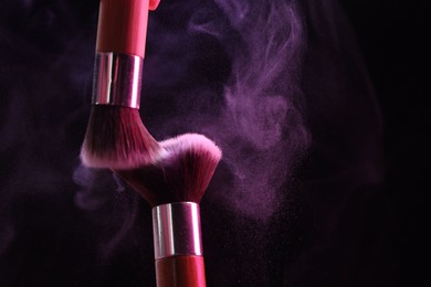 Photo of Makeup brushes with color eye shadow on black background, closeup. Space for text