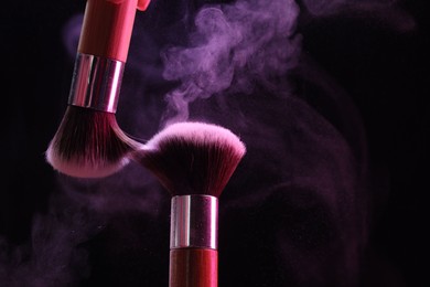 Photo of Makeup brushes with color eye shadow on black background, closeup