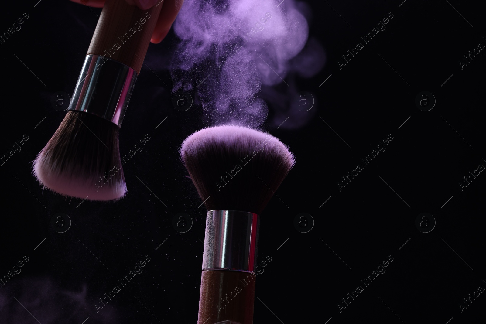 Makeup brushes with purple eye shadow on black background, closeup Photo of Makeup brushes with purple eye shadow on black background, closeup