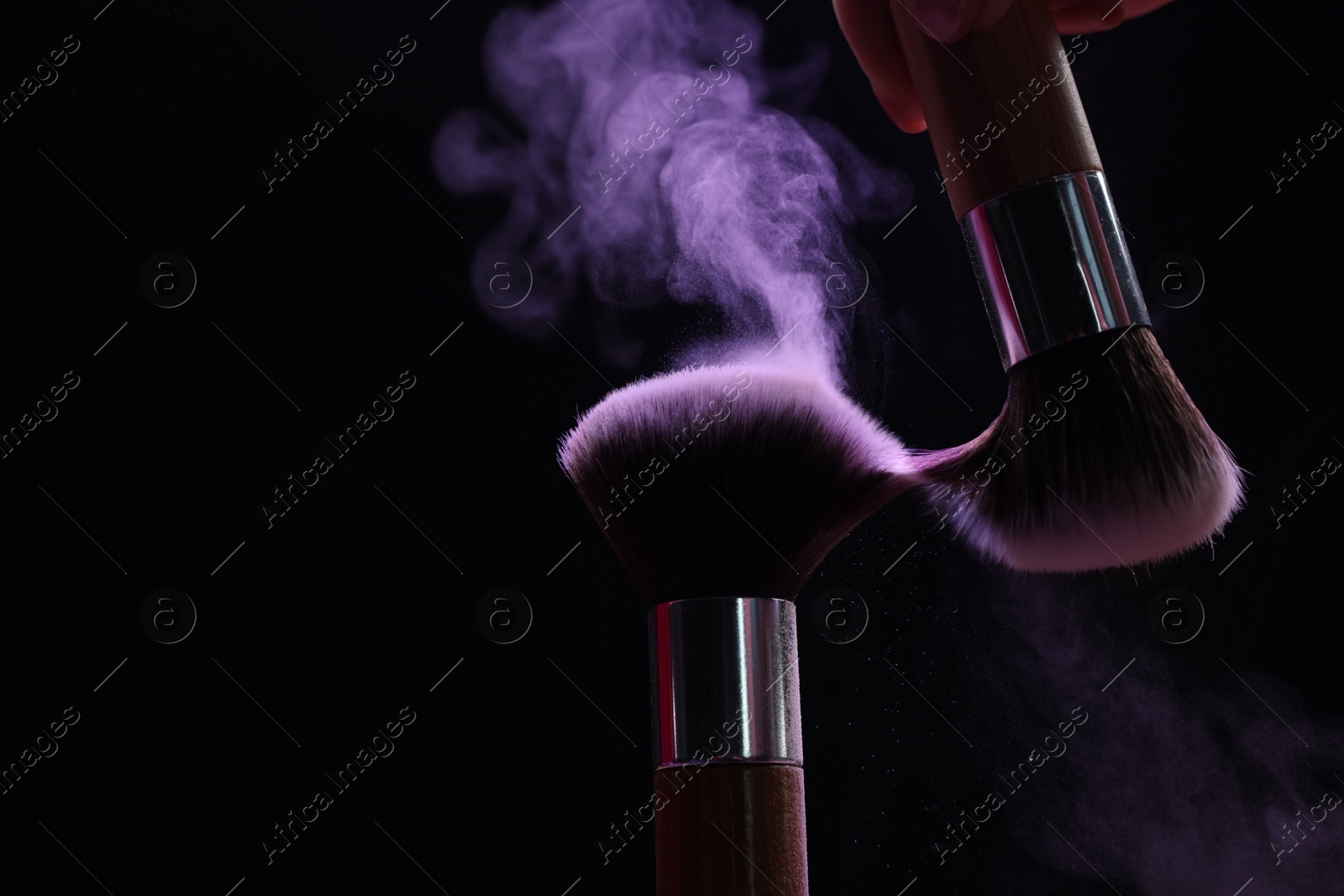 Makeup brushes with purple eye shadow on black background, closeup Photo of Makeup brushes with purple eye shadow on black background, closeup