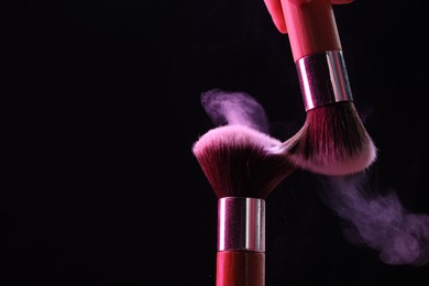 Photo of Makeup brushes with color eye shadow on black background, closeup. Space for text