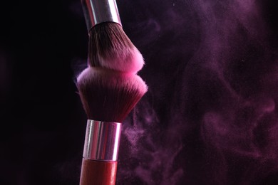 Photo of Makeup brushes with color eye shadow on black background, closeup. Space for text