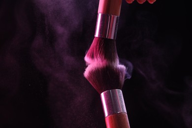 Photo of Makeup brushes with color eye shadow on black background, closeup