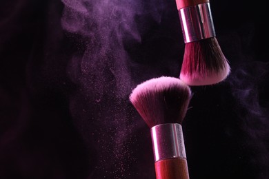Photo of Makeup brushes with color eye shadow on black background, closeup. Space for text