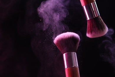 Photo of Makeup brushes with color eye shadow on black background, closeup. Space for text
