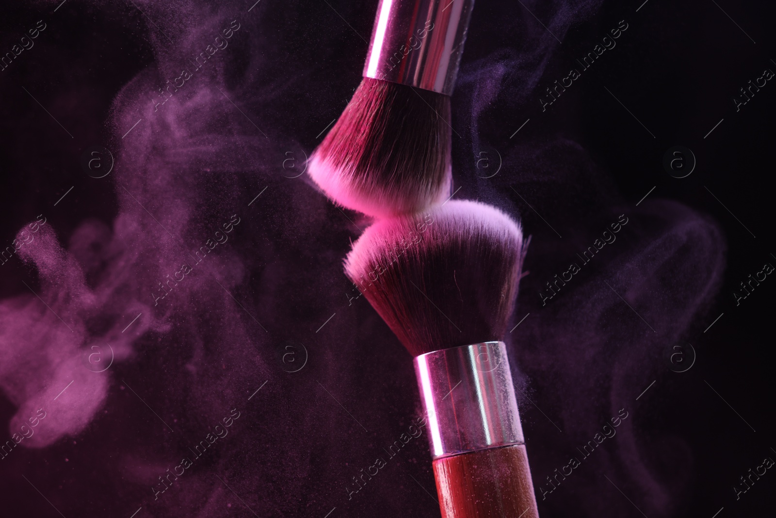 Makeup brushes with colorful eye shadows in neon lights on black background, closeup Photo of Makeup brushes with colorful eye shadows in neon lights on black background, closeup