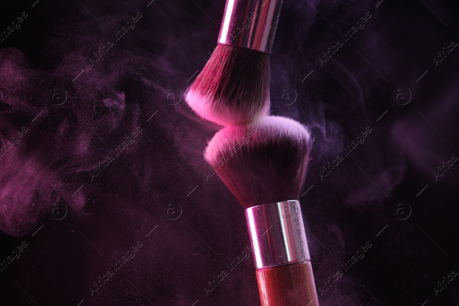 Makeup brushes with colorful eye shadows in neon lights on black background, closeup. Space for text Photo of Makeup brushes with colorful eye shadows in neon lights on black background, closeup. Space for text