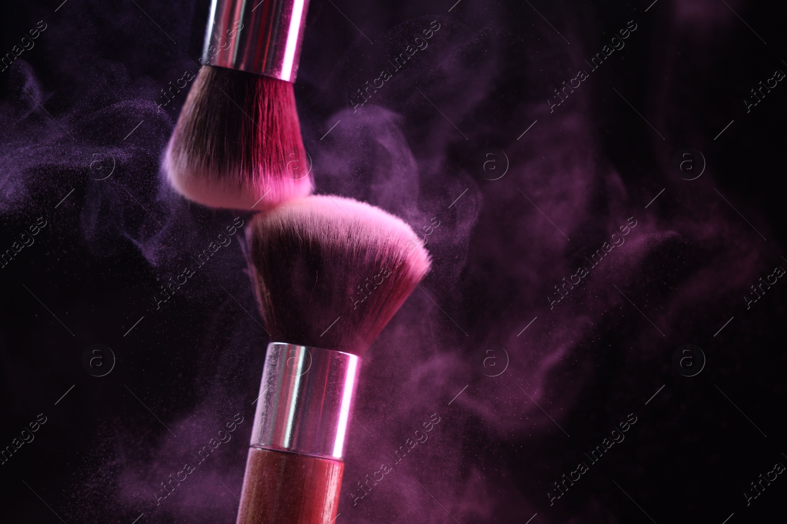 Makeup brushes with colorful eye shadows in neon lights on black background, closeup. Space for text Photo of Makeup brushes with colorful eye shadows in neon lights on black background, closeup. Space for text
