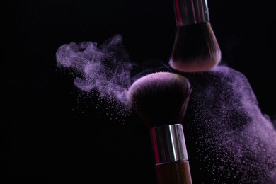 Photo of Makeup brushes with purple eye shadow on black background, closeup. Space for text
