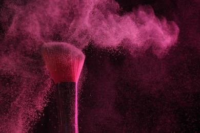 Photo of Makeup brush with pink eye shadow on black background, closeup