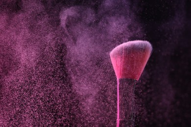 Photo of Makeup brush with pink eye shadow on black background, closeup. Space for text